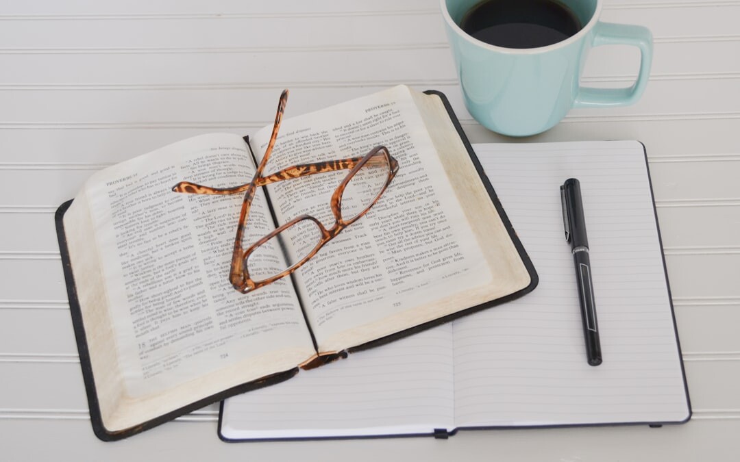 Open notebook with a pen and a cup of coffee on a desk
